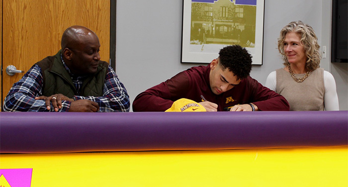 Peter Udoibok signs his U of M paperwork while his proud parents, Kenneth and Meredith, watch.