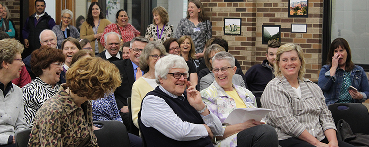 Brother Michael Rivers and Donna Novey listen to speakers reminiscing on their many years of service at CDH, surrounded by family, friends, and fellow staff.